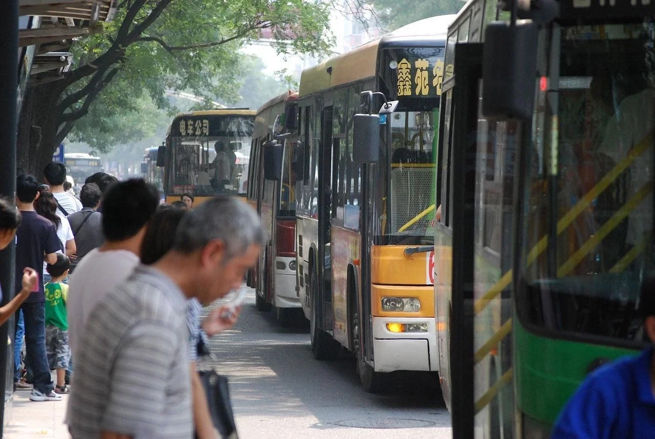 Passengers waiting to board city buses at a bus stop
